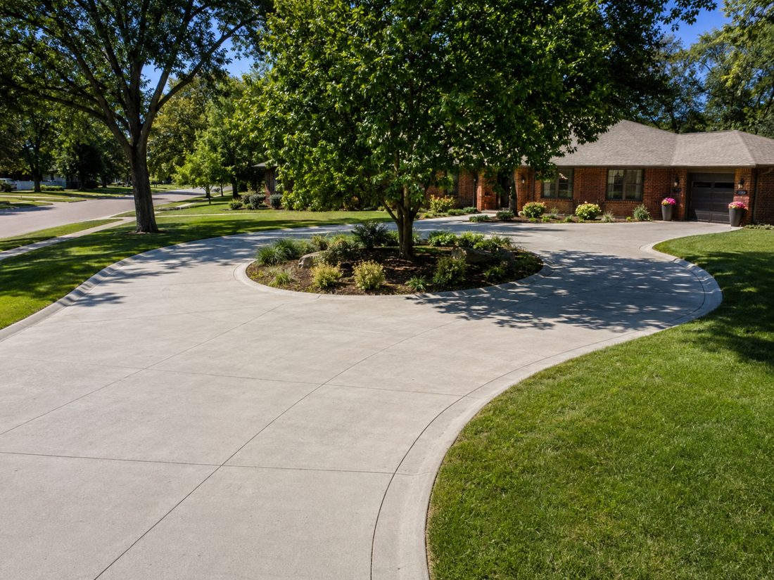 Curved concrete circle driveway around a landscaped island at a brick home in Sioux Falls, SD